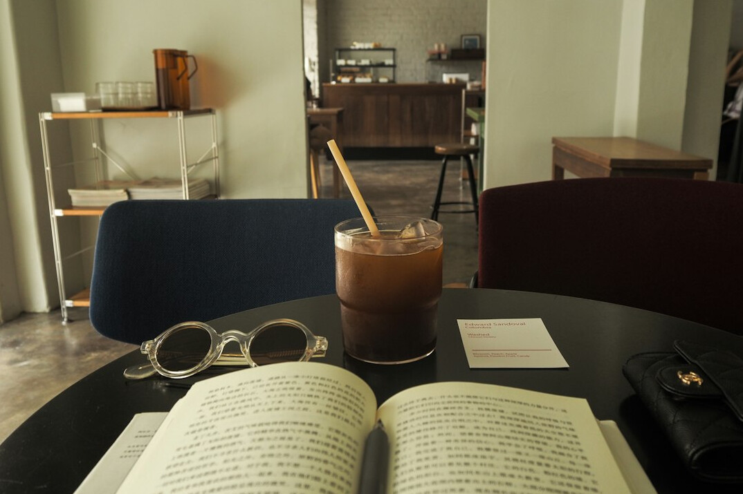 Open mystery novel with reading glasses on a cafe table