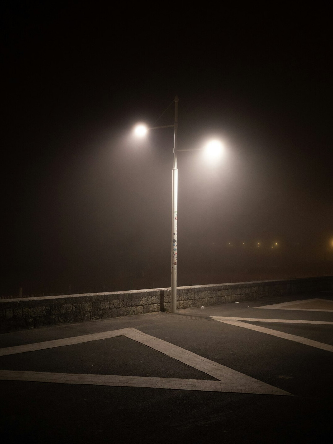 Foggy empty street at night with a single lit lamppost