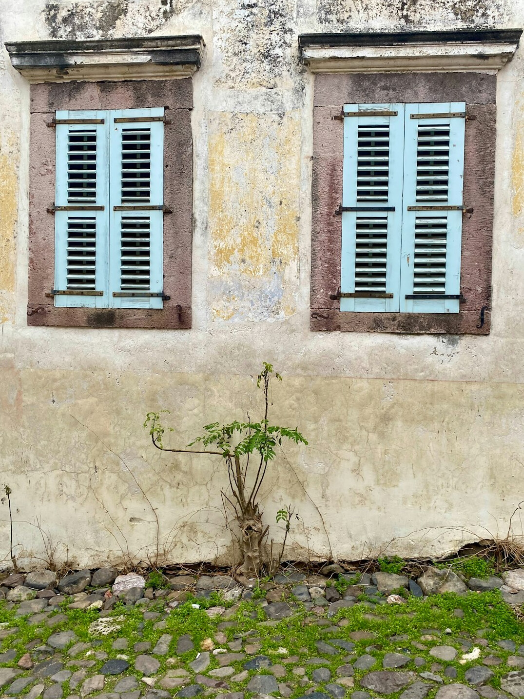 Weathered colonial building facade with old wooden shutters
